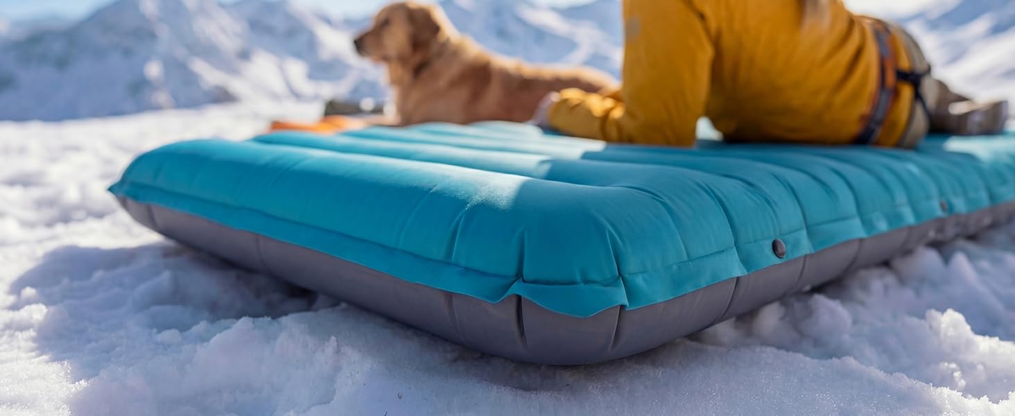 Side view of thick Airlive2000 pad on snow as users lounge with dog.