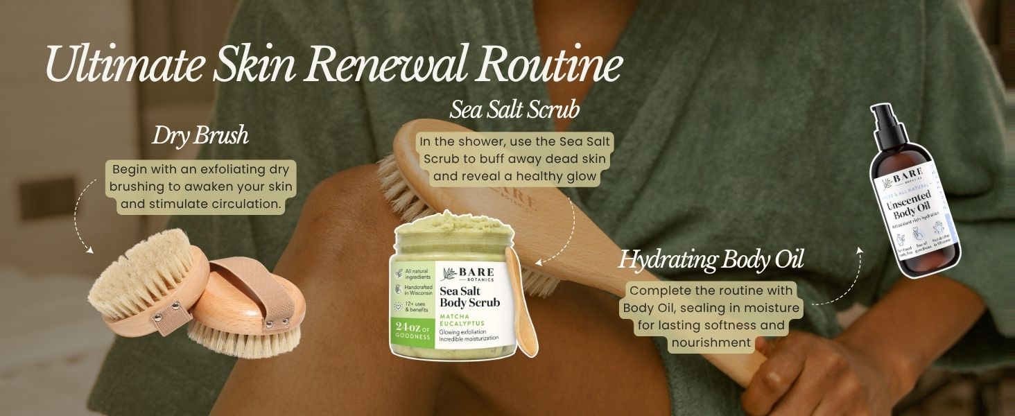 a woman wearing a green bath robe dry brushing their leg using a long handle body brush