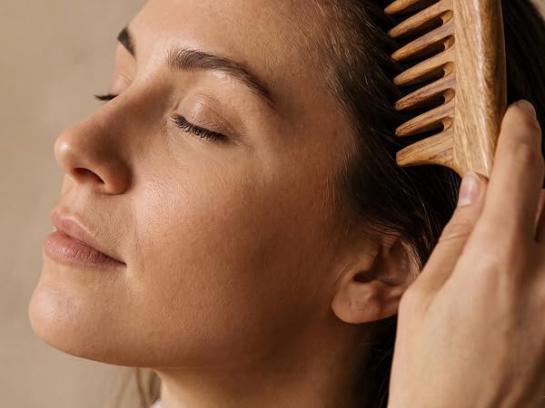Natural wooden wide-tooth comb gliding through hair for gentle daily detangling.