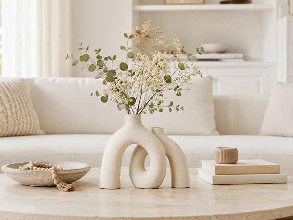 Cream ceramic donut vase with flowers on a living room coffee table.