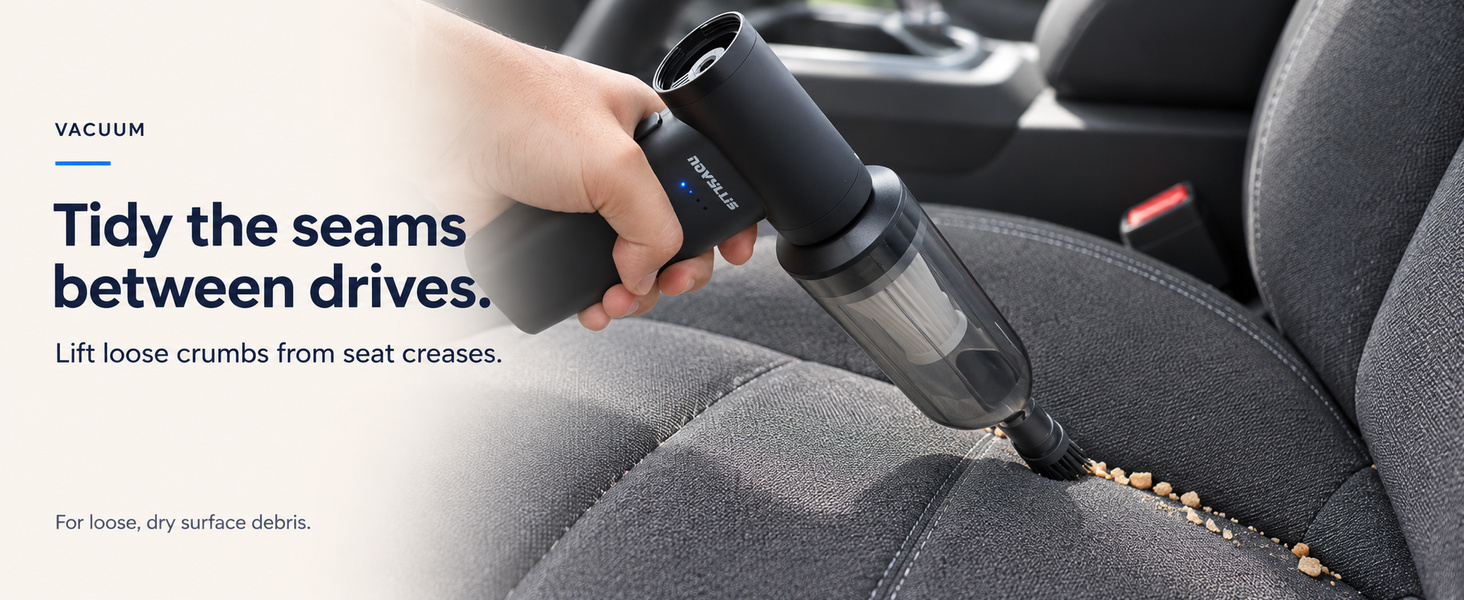 Cordless handheld vacuum collecting loose dry crumbs from fabric car seat seams