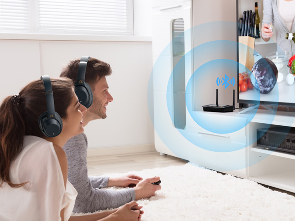 Two people wearing headphones sit in front of a device emitting blue waves, suggesting a wireless audio system or gaming setup.