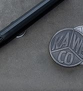 Close-up of a dark circular embossed logo or emblem against a gray background, appears to be a branded surface detail.