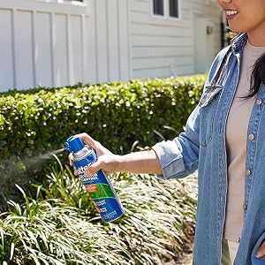 Lifestyle image of user spraying the Backyard Bug Control Fogger around shrubs