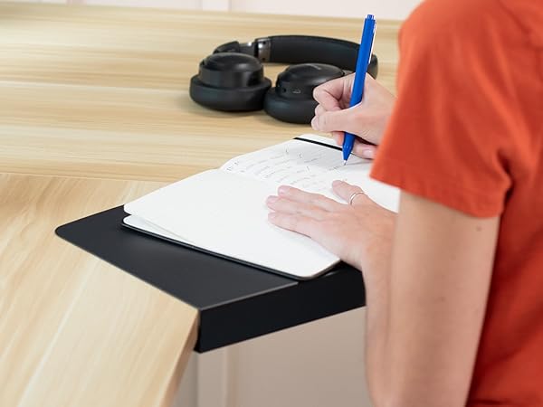 woman writing in notepad on corner desk