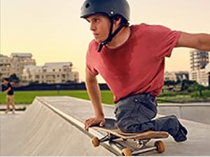 A male para-athlete on a skateboard, sweating and posing confidently on top of a large ramp.