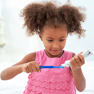 Girl putting toothpaste on toothbrush