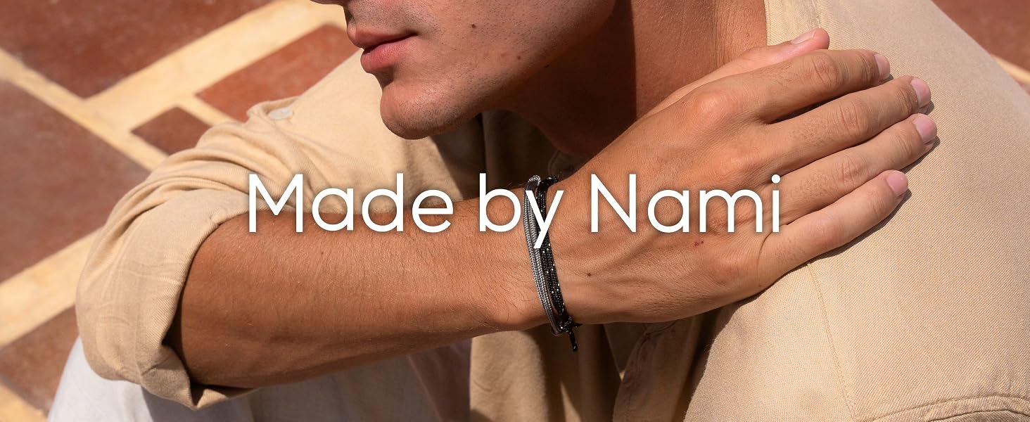 Man wearing a beige shirt and black nautical rope bracelet with silver details on his wrist.