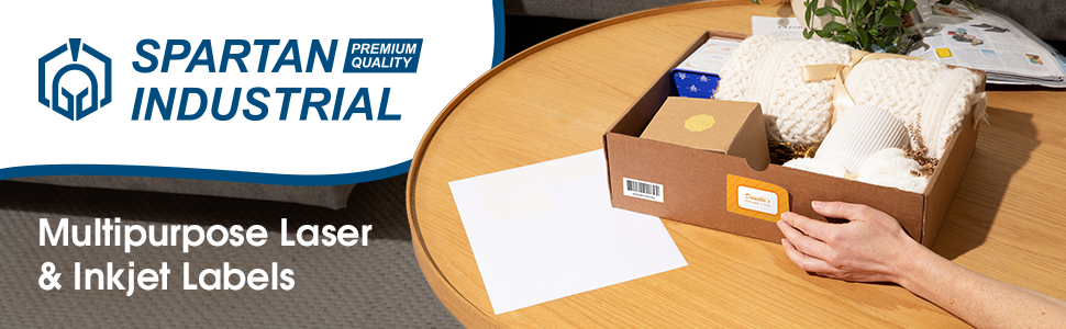 A hand applying a colorful label sticker to an open box on a table next to a sheet of white labels