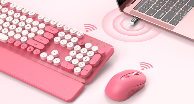 Pink round-key keyboard and matching mouse connected wirelessly to a laptop with a USB receiver.