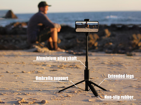 Text reads: 'Aluminum alloy shaft', 'Umbrella support', 'Extended legs', 'Non-slip rubber'. Portable phone stand with tripod legs shown on beach sand at sunset.