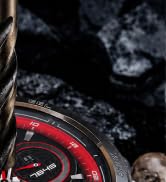 Close-up detail shot showing dark textured surface with red circular design element, partially visible against black background. Image lacks sufficient context for definitive product identification.