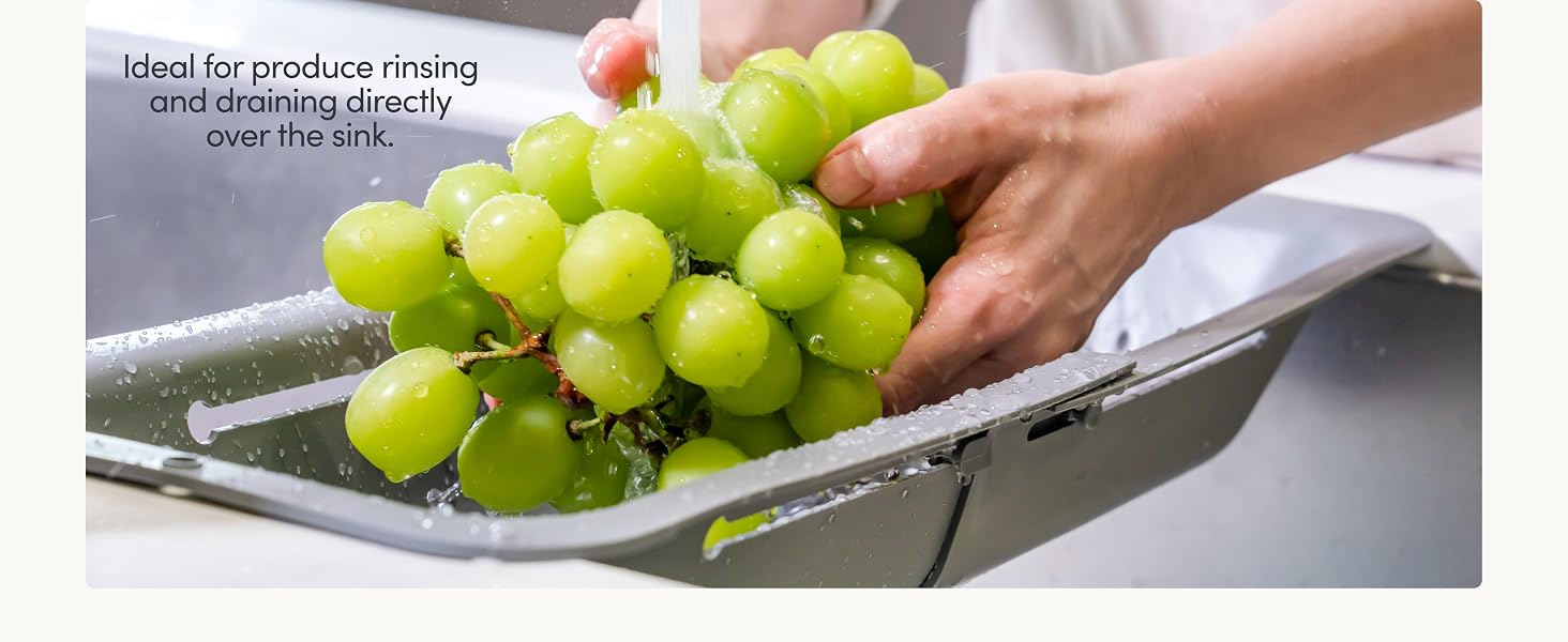 Sink colander expanded across sink rinsing fruit and produce while draining