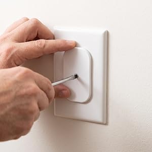 Adult hand securing a baby proof outlet cover to a standard duplex outlet with a screwdriver