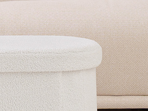 Partial view of a white or cream-colored cylindrical container or storage box with lid against a beige background.