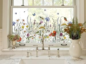 Bright, sunlit window sill with multiple clear glass vases containing wildflowers and greenery, creating a natural decorative display.