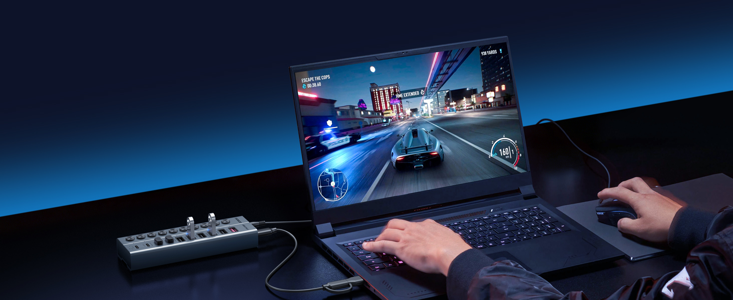 Gaming setup with illuminated blue racing game displayed on monitor, mechanical keyboard, mouse, and controller visible on desk during nighttime gameplay session.