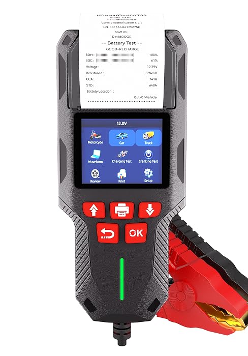 Automotive diagnostic scanner device with LCD screen displaying blue menu icons, black housing with red control buttons labeled 'OK', and red diagnostic connector attachment. Device appears to be a professional vehicle diagnostic tool.