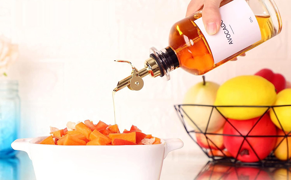 a hand pouring oil into a bowl of carrots.