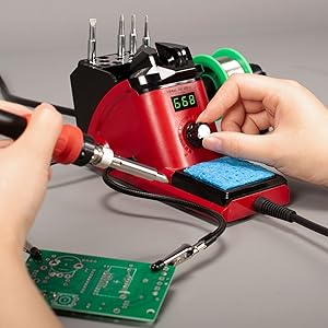 A man is turning the knob of the YIHUA 926LED-III 110W to set the desired temperature