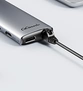 Close-up of a silver USB-C hub or adapter connected to a cable. The sleek metal device has multiple ports visible on its side.