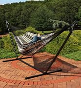 black and white handwoven thick woven cord hammock with women laying on it on a brick patio