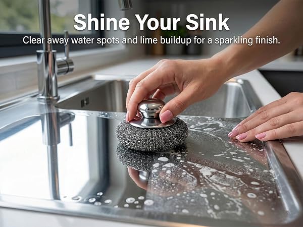 Metal sponge cleaning water spots and limescale from stainless steel kitchen sink.