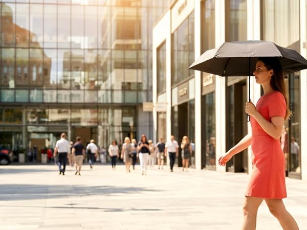 Woman in red dress with black compact umbrella walking in modern urban plaza setting