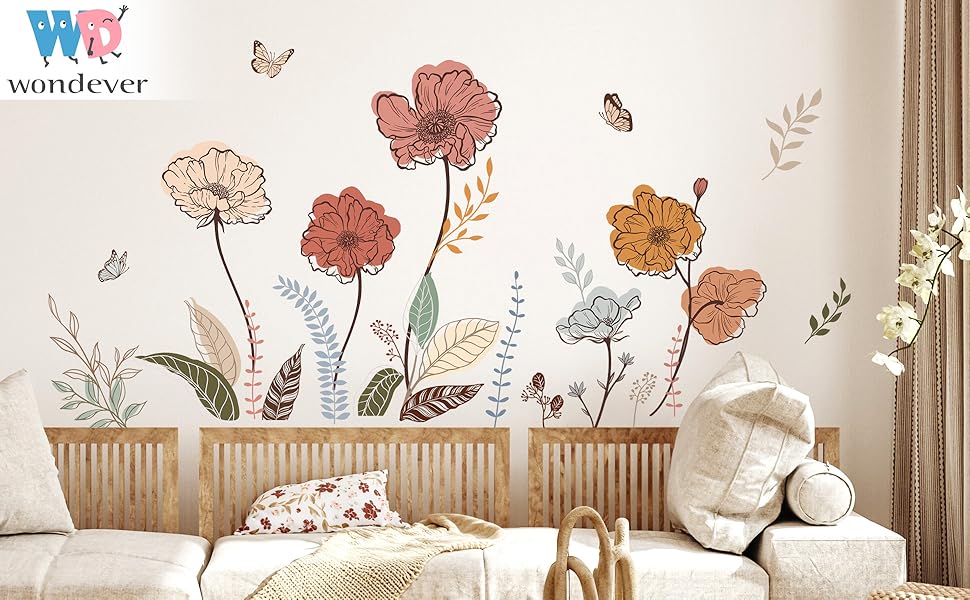 Wall decal set featuring large floral designs in shades of orange and brown. Butterflies and stems included. Displayed on white wall above furniture.