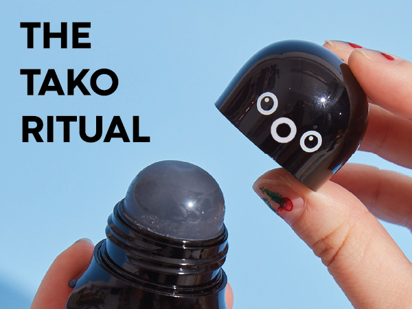 Hands opening the Tako Pore Scrub Stick on a blue background beneath "The Tako Ritual" headline