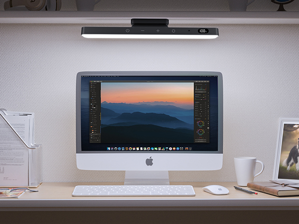 Modern workspace setup with iMac computer displaying photo editing software, wireless keyboard and mouse, mounted light bar above screen.