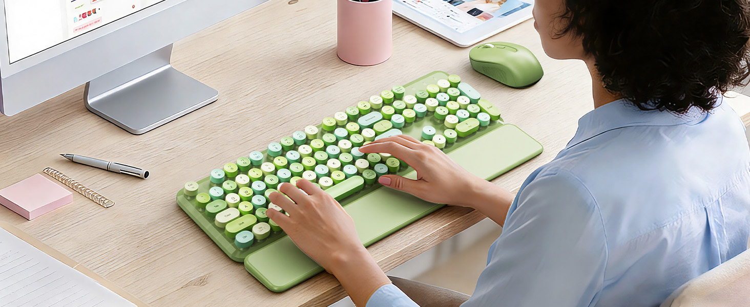 Person using green keyboard with wrist rest and mouse at a clean desk workspace