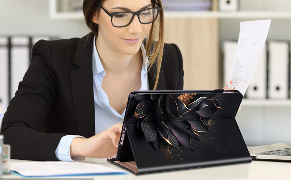 Professional woman in business attire working on a tablet with floral design case. Office setting with binders visible in background.