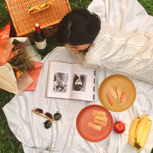 a woman laying on a blanket reading a book.