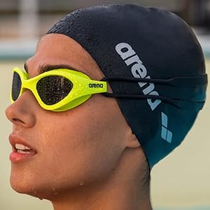 close-up of woman wearing a black arena swim cap and neon yellow arena swim goggles in the summer