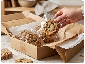 Hand placing a cello-wrapped cookie into a shipping box of individually bagged cookies