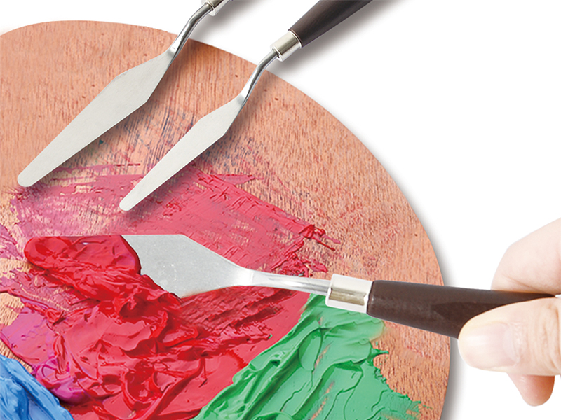 a close up of a person's hand holding paint brushes