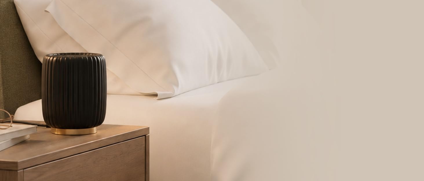A wax warmer sits on a bedside table in a modern bedroom