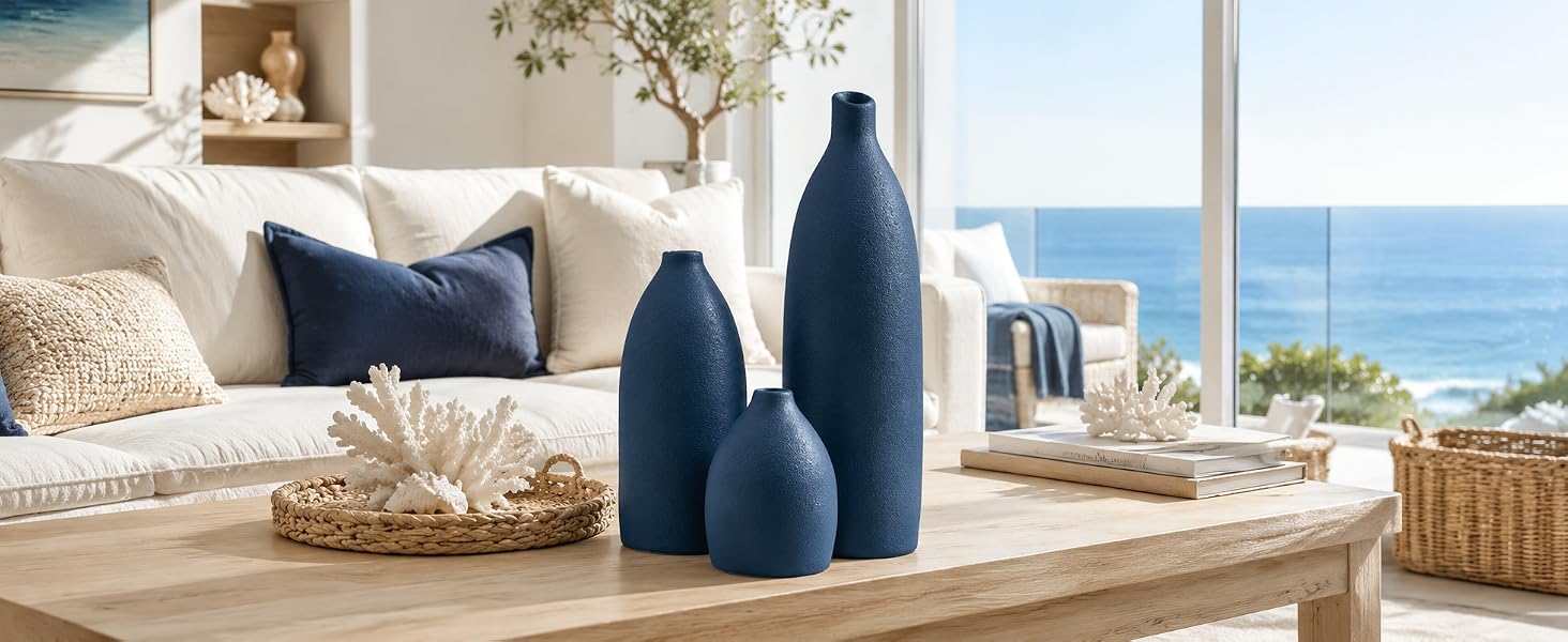 Navy blue bullet-shaped vase set on a coastal kitchen counter with ocean view and shells.