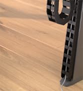 Close-up of a black metal ladder-like structure on light wood flooring. The structure has multiple horizontal rungs and appears to be part of exercise equipment.