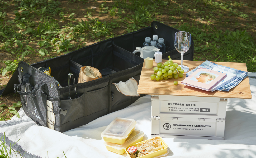 Open NINEDUCK trunk organizer in an outdoor picnic setup with drinks, snacks, and small items.