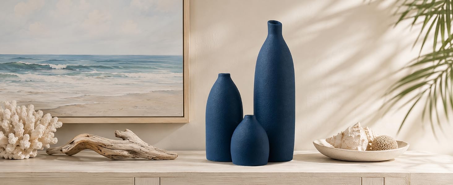 Navy blue bullet-shaped vase set with driftwood, coral, and shells for coastal decor.