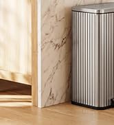 Tall rectangular air purifier unit with vertical ribbed design in silver/grey finish positioned on light wooden floor against white wall background.