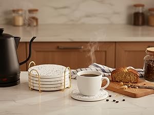 Absorbent ceramic coasters stacked beside coffee mug and kettle on kitchen counter