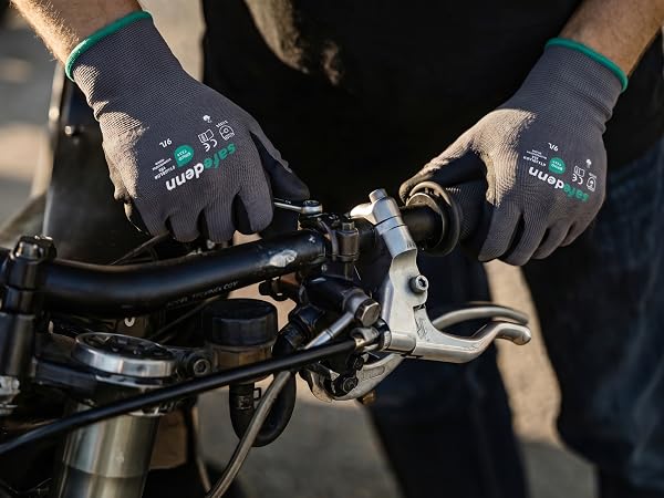 Safedenn nitrile-coated mechanic gloves being used with a wrench for motorcycle engine repair.