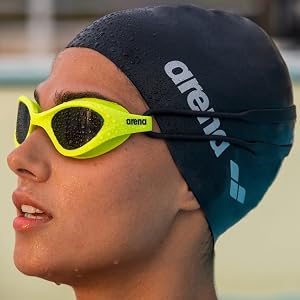close-up of woman wearing a black arena swim cap and neon yellow arena swim goggles in the summer