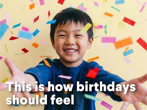 Happy young boy smiling with colorful confetti falling all around him