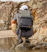 Outdoor adventure backpack promotion. Person wearing gray backpack sits on rocky shore overlooking water, with promotional text in German.