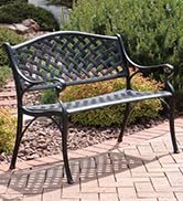 checkered cast aluminum outdoor bench on brick patio with lush landscaping
