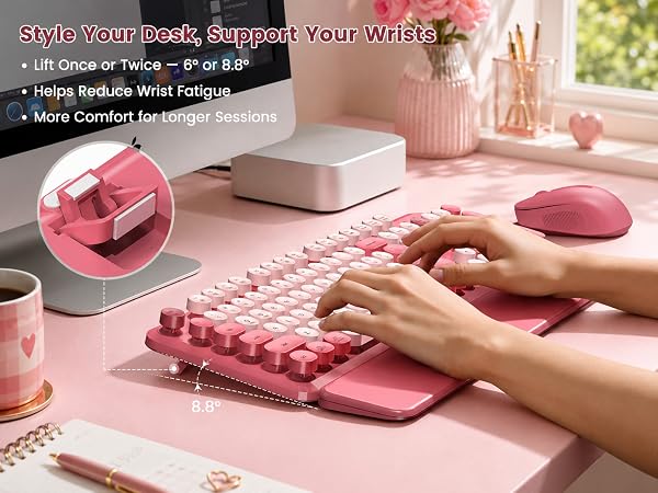 Pink round-key keyboard and matching mouse with wrist rest used on a blush desk for angled typing.